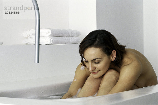 Frau im Bad sitzend mit Kopf auf Knien  Augen geschlossen