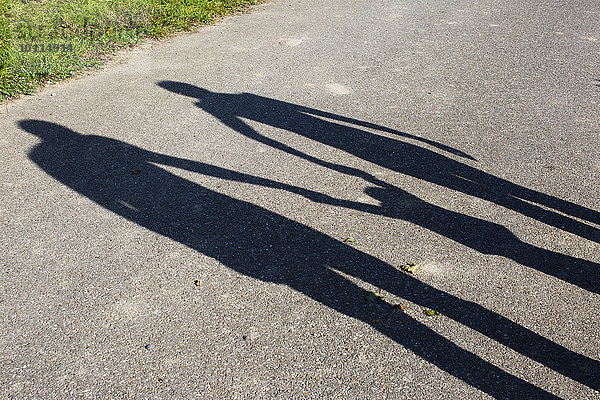 Schatten einer Familie  die im Freien Händchen hält.