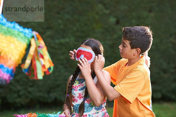 Kinder spielen Pinata im Garten