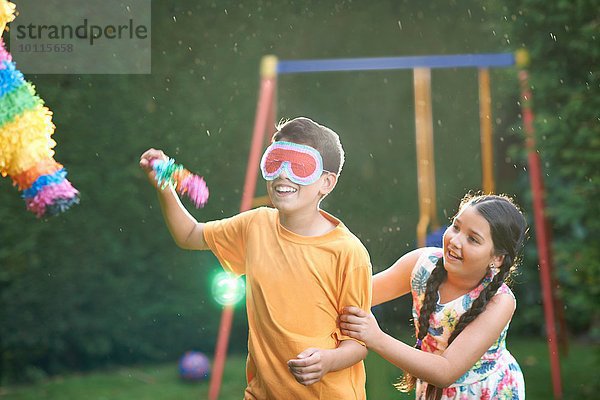 Kinder spielen Pinata im Garten