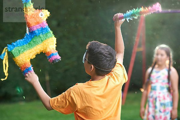 Kinder spielen Pinata im Garten