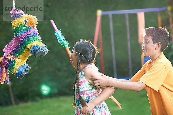 Kinder spielen Pinata im Garten