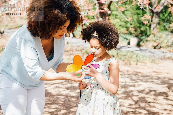 Mutter helfende Tochter mit farbenfrohem Pinwheel-Spielzeug