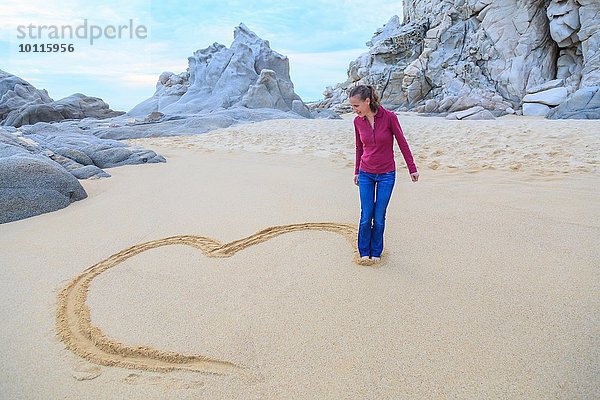 Mittlere erwachsene Frau am Strand  Zeichnung Herzform mit Füßen