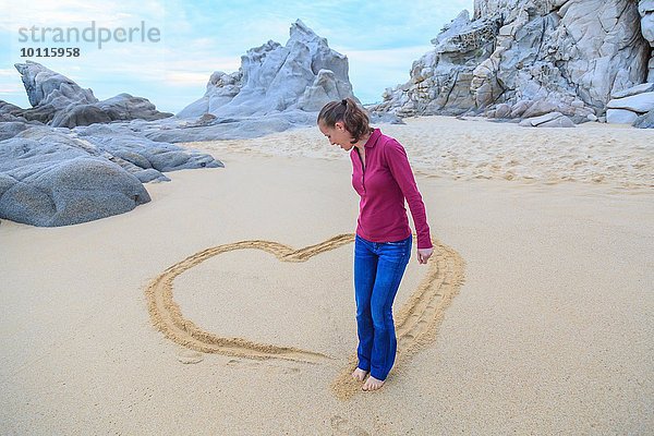 Mittlere erwachsene Frau am Strand  Zeichnung Herzform mit Füßen