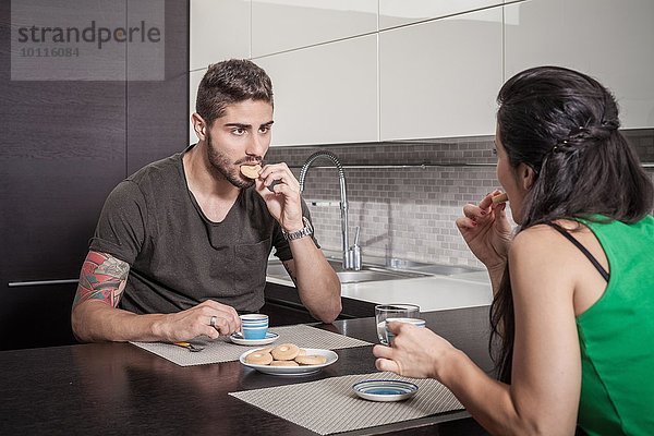 Junges Paar trinkt Kaffee und isst Kekse an der Frühstückstheke