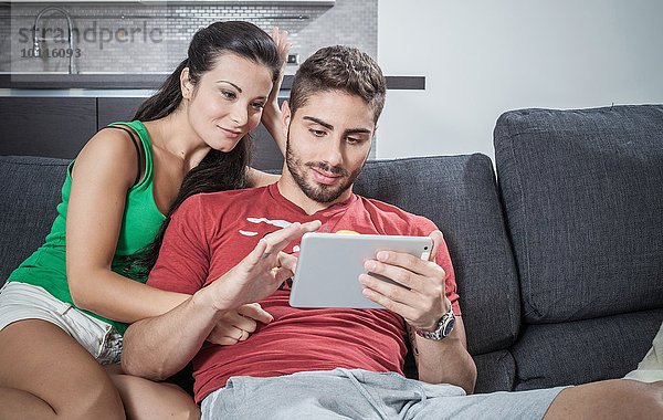 Junges Paar auf Sofa mit digitalem Tablett