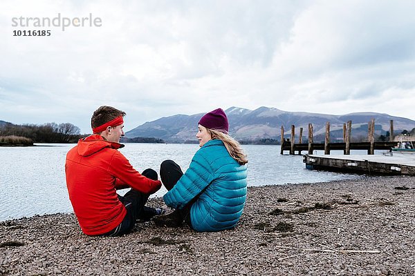 Junges Paar beim Wandern  am Wasser sitzend  Derwent Water  Keswick  Lake District  Cumbria  Großbritannien