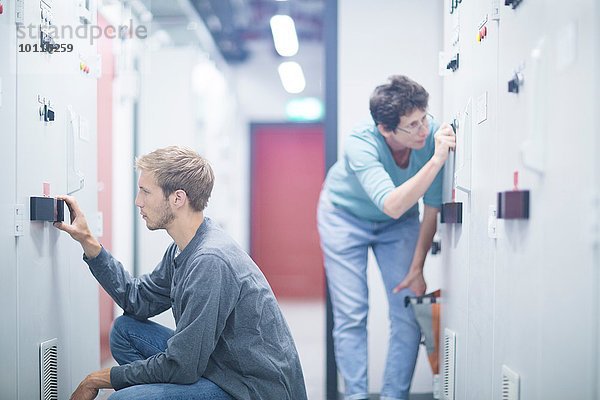 Techniker und Technikerinnen beim Drehen von Schaltern im Technikraum