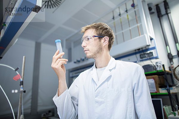 Junger Wissenschaftler beim Betrachten der Probenflasche im Labor