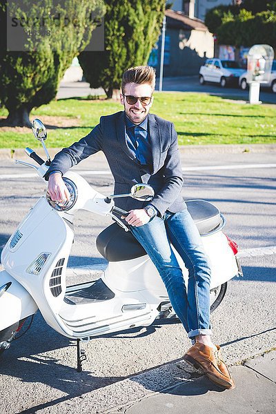 Porträt eines stilvollen jungen Mannes auf Moped