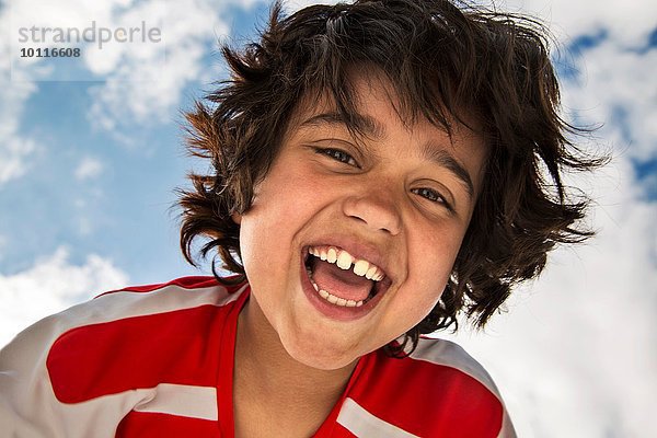 Flachwinkel-Porträt des lächelnden Jungen vor dem Himmel