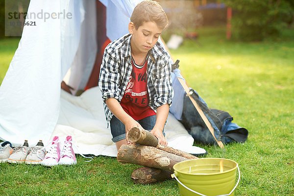 Junge bereitet Baumstämme für Lagerfeuer im Garten vor