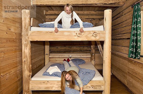 Zwei junge Freundinnen  die auf Etagenbetten im Blockhaus herumalbern