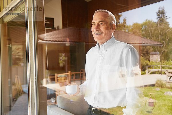 Senior Mann zu Hause  Kaffee trinken  aus dem Fenster schauen