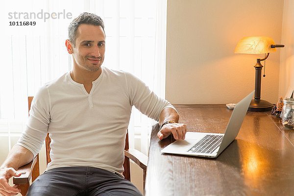 Mittlerer Erwachsener Mann am Schreibtisch sitzend  mit Laptop