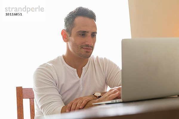 Mittlerer Erwachsener Mann am Schreibtisch sitzend  mit Laptop