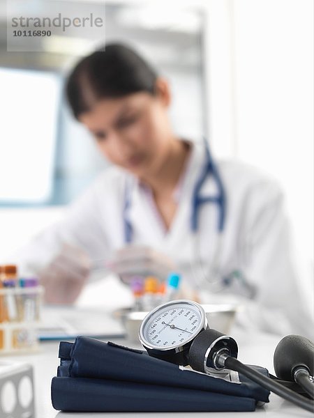 Ärztin untersucht Reagenzglas am Schreibtisch in der Klinik