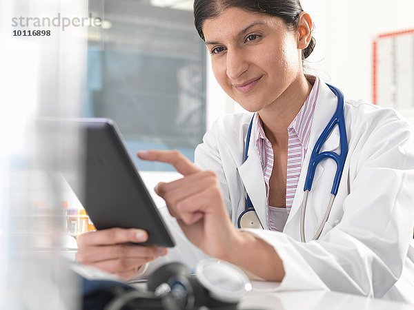 Ärztin mit digitalem Tablett-Touchscreen zur Aktualisierung von Krankenakten