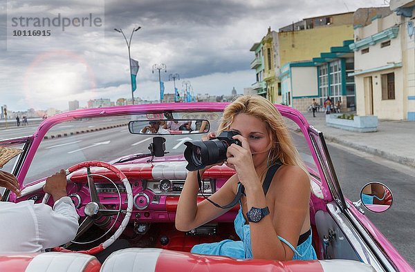 Junge Frau fotografiert aus einem Oldtimer auf dem Havanna' Malecon  Kuba