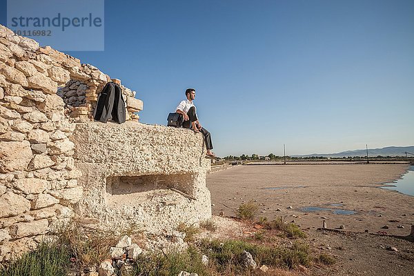 Mittlerer Erwachsener Geschäftsmann  der von der Strandmauer auf das Meer blickt.