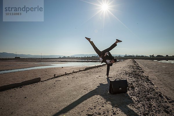 Mittlerer erwachsener Geschäftsmann beim Handstand am Strand