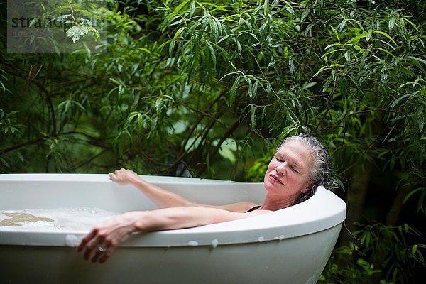 Reife Frau entspannt sich im Garten-Sprudelbad im Öko-Retreat