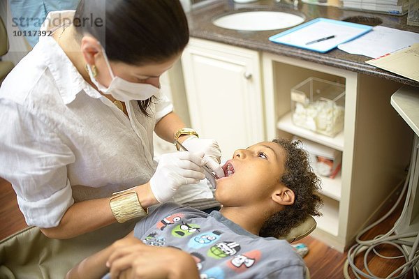 Kieferorthopädin untersucht Junge in der Zahnarztpraxis