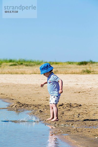Kleiner Junge am Strand  der Sand ins Meer wirft  Marennes  Charente-Maritime  Frankreich