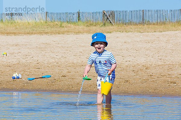 Portrait eines kleinen Jungen  der Meerwasser im Spielzeugeimer am Strand sammelt  Marennes  Charente-Maritime  Frankreich