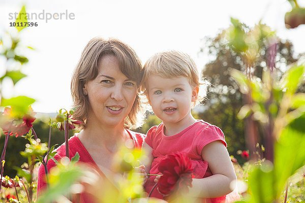 Porträt der mittleren erwachsenen Mutter und Kleinkind-Tochter im Blumenfeld