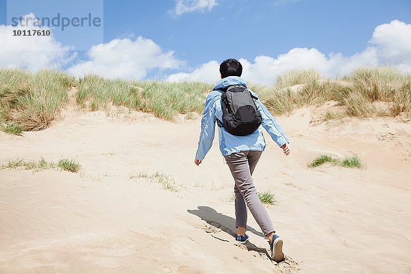 Rückansicht der mittleren erwachsenen Wanderin  die die Sanddüne hinaufgeht