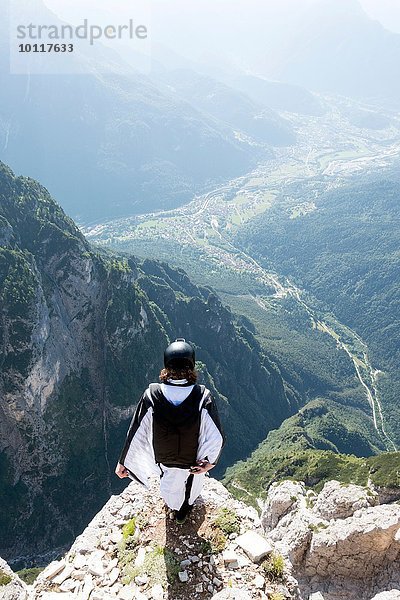 Männlicher BASE Pullover im Wingsuit stehend am Bergrand  Dolomiten  Italien