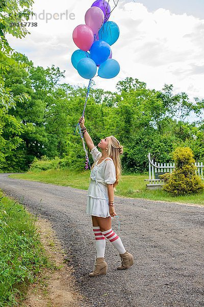 Junge Frau blickt auf einen Haufen Ballons auf der Landstraße