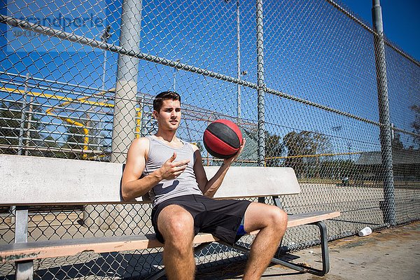 Junger Basketballspieler macht Pause auf der Bank