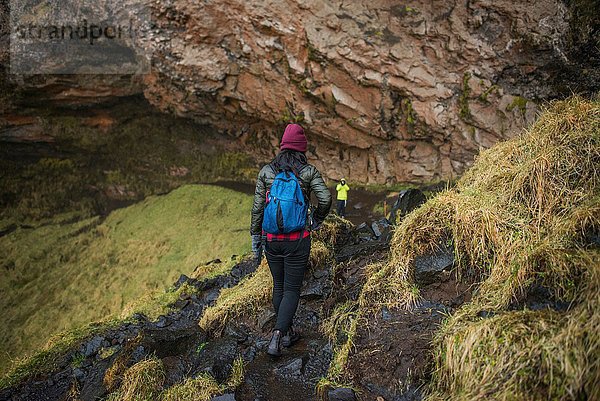 Zwei Touristen wandern am Seljalandsfoss Wasserfall  Island