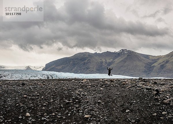 Silhouette der weiblichen Touristen  die vor dem Gletscher springen  Skaftafell  Island