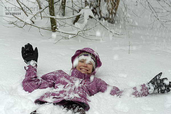 Mädchen liegt im Schnee im Winter  Oberbayern  Bayern  Deutschland  Europa