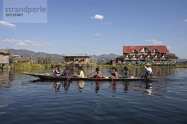 Einheimische Frauen in einem Holzboot paddeln auf dem Inle-See  hinten Stelzenhäuser  Inle-See  Shan-Staat  Myanmar  Asien