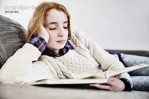 Mädchen liegt zuhause auf dem sofa und liest ein Buch  Köln  Nordrhein-Westfalen  Deutschland  Europa