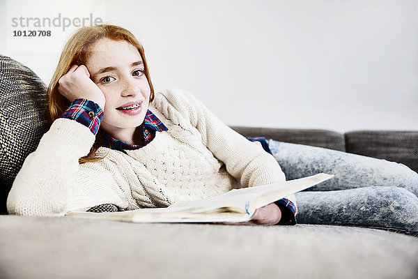 Mädchen liegt zuhause auf dem sofa und liest ein Buch  Köln  Nordrhein-Westfalen  Deutschland  Europa