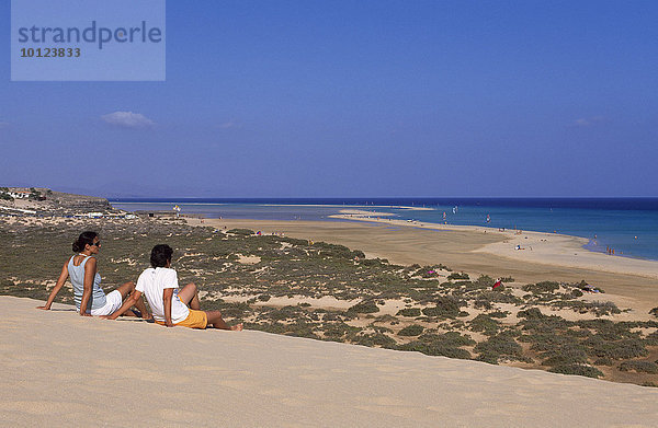 Zwei Menschen sitzen auf Sanddüne bei den Playas de Sotavento  Fuerteventura  Kanarische Inseln  Spanien  Europa