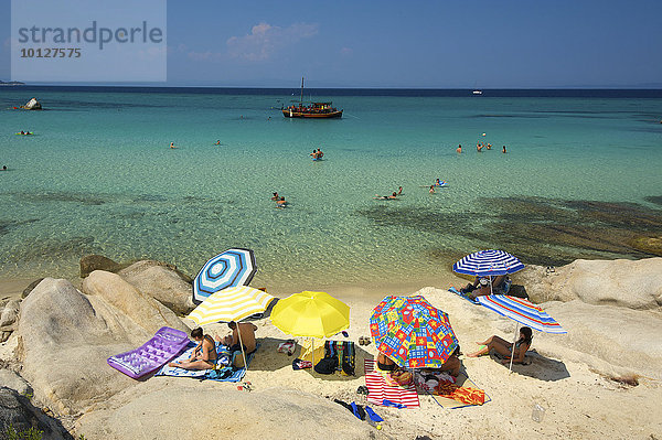 Urlauber mit Sonnenschirmen am Strand von Portokali  Kavourotypes  Sithonia  Chalkidiki  Griechenland  Europa