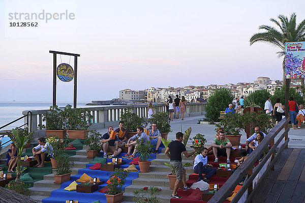 Menschen sitzen auf Treppe an der Promenade  Abendstimmung  Cefalù  Provinz Palermo  Sizilien  Italien  Europa