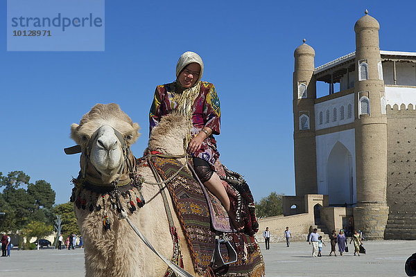 Einheimische Touristin auf Kamel vor der Zitadelle Ark  Buchara  Usbekistan  Asien