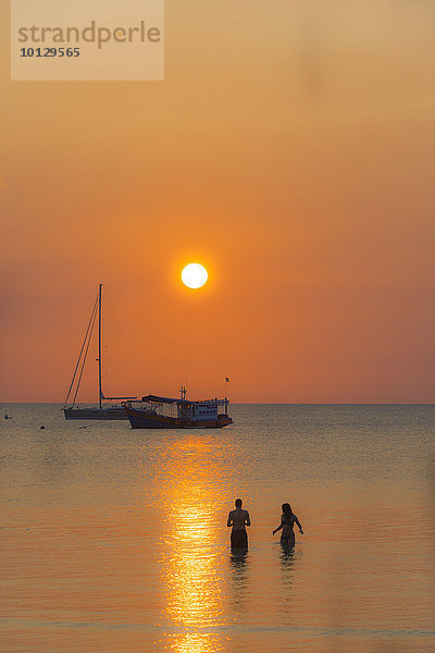 Zwei Menschen stehen im Wasser  Boote im Meer bei Sonnenuntergang  Insel Koh Tao  Golf von Thailand  Thailand  Asien