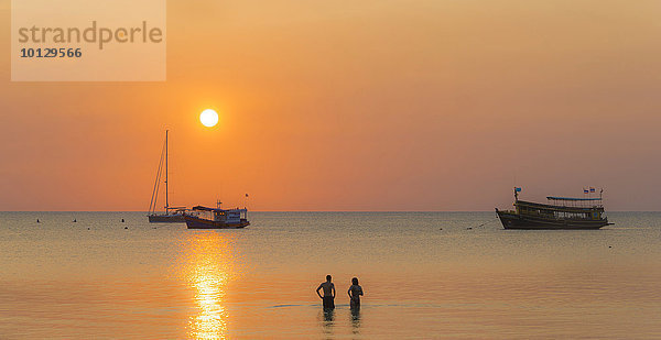 Zwei Menschen stehen im Wasser  Boote im Meer bei Sonnenuntergang  Insel Koh Tao  Golf von Thailand  Thailand  Asien