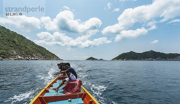 Einheimischer Mann sitzt am Heck und steuert ein Longtail-Boot im türkisen Meer  Insel Koh Tao  Golf von Thailand  Thailand  Asien