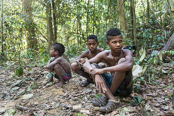 Drei Jungen der Orang Asil sitzen auf dem Boden im Dschungel  Ureinwohner  indigenes Volk  tropischer Regenwald  Nationalpark Taman Negara  Malaysia  Asien