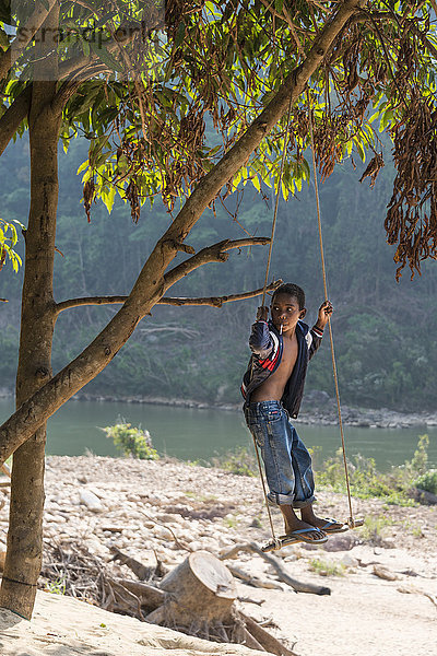 Kleiner Junge  Volksstamm Orang Asil  Ureinwohner schaukelt und schaut in die Ferne  Nationalpark Taman Negara  Malaysia  Asien